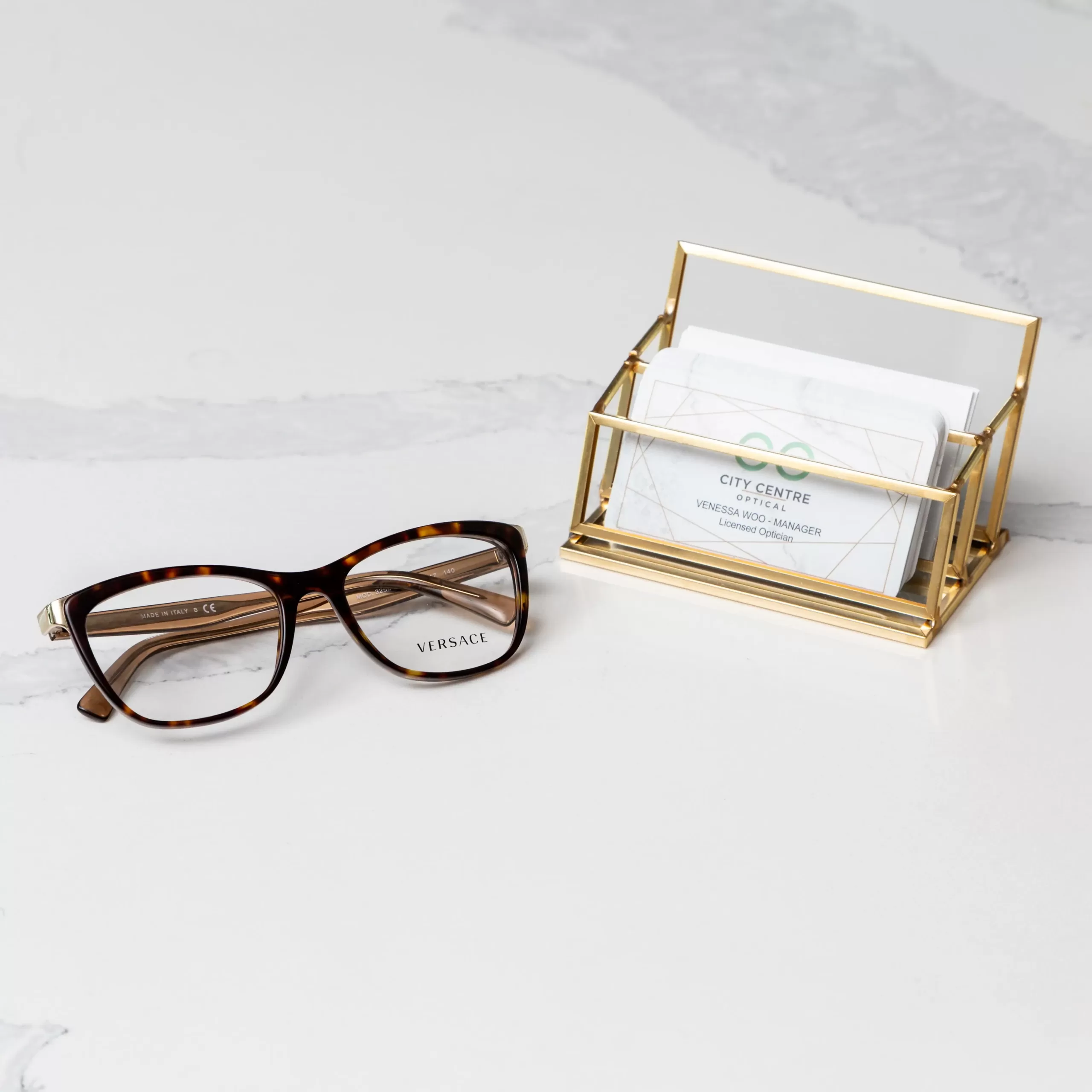 pair of Versace glasses placed beside stack of City Centre Optical - Surrey, B.C. cards